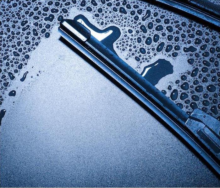 "a close-up image of a wiper blade wiping away condensation on a car windshield”  