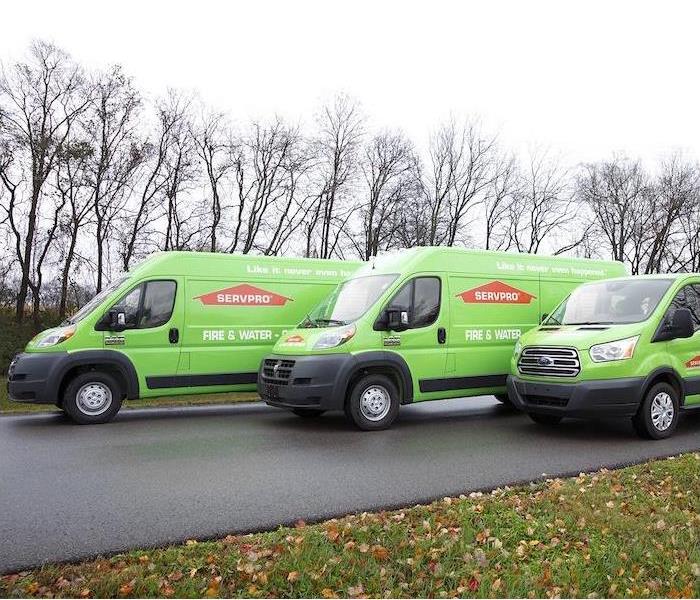  "three green SERVPRO trucks lined up on a side street”